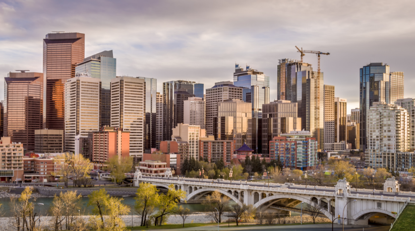 Bridge leading into downtown Calgary with office buildings and Calgary skyline at sunset.